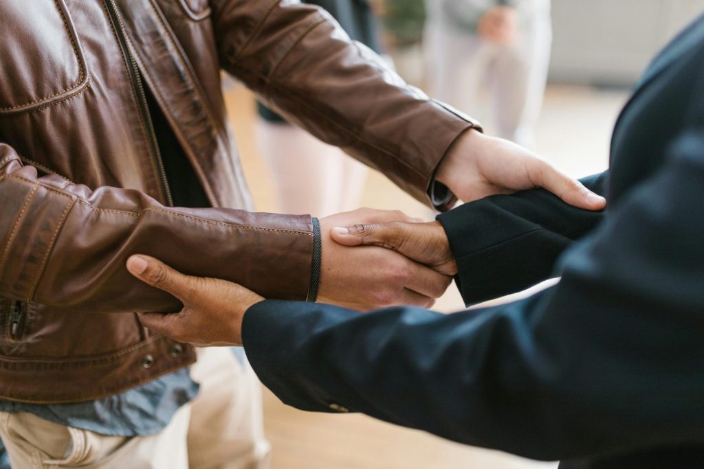 Two business professionals shaking hands, symbolizing teamwork and collaboration indoors.