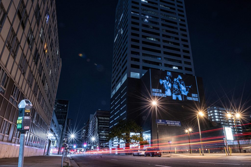a city street at night with a tall building in the background